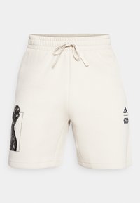 Krämfärgade bomullsshorts med elastisk midja och dragsko. Har en svart grafik och logotyp på ena sidan. Slät textur, avslappnad passform.