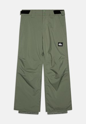 Pantalon de neige vert olive avec des sangles ajustables en Velcro à la taille, deux poches avant et un petit écusson logo noir et blanc sur la jambe droite.