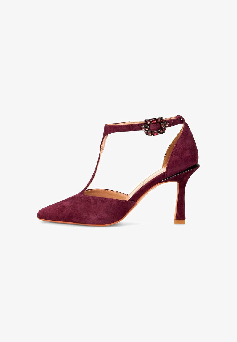 Scarpa con tacco alto in suede bordeaux, punta affusolata, design a T-strap, dettaglio in metallo con gioielli e un elegante tacco a stiletto.
