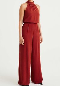 Röd halter jumpsuit med en strukturerad finish, som har en figurnära bodice och vida byxor, med skräddarsydda veck vid midjan.