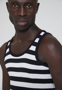 Stribet tanktop i sort og hvid, tætsiddende design med ribbet tekstur, med brede skulderstropper og rund halsudskæring.