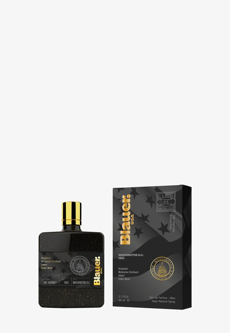 Bouteille en verre noir avec des accents dorés, présentant une finition texturée et une forme carrée. Accompagnée d'une boîte noire rectangulaire avec un motif d'étoiles.