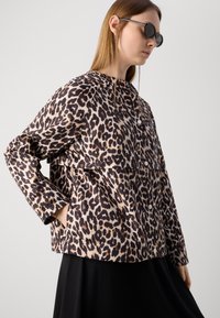 Jachetă cu model leopard din material satinat, având o croială lejeră, mâneci lungi și închidere cu capse. Model texturat în nuanțe de marron și bej.