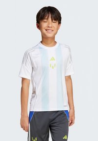 Camisola branca de manga curta com riscas verticais azul claro, apresentando um logótipo verde no peito. Usada com calções desportivos cinzentos.