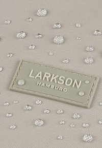 Szary materiał z wypukłymi, przezroczystymi kryształkami w różnych rozmiarach. Posiada teksturowaną metkę z białym wytłoczonym napisem "LARKSON HAMBURG".