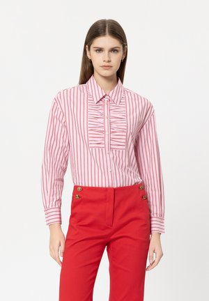 Red and white striped shirt with a ruffled front panel, classic collar, and long sleeves, paired with high-waisted red pants featuring gold buttons.