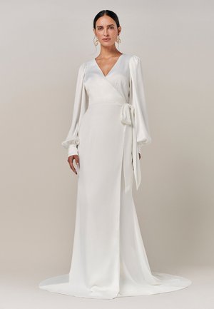 Weißes Wickelkleid mit tiefem V-Ausschnitt, langen Puffärmeln und seitlichem Bindeband. Glattes, fließendes Material mit einem bodenlangen Saum und minimalistischem Design.