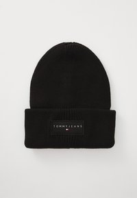 Black knitted beanie with a folded cuff, featuring a rectangular patch labeled "TOMMY JEANS" in white text and a small logo in red, white, and blue.