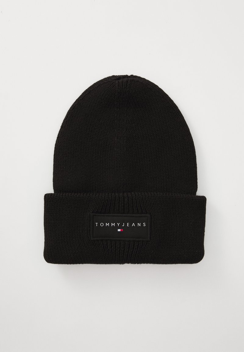 Black knitted beanie with a folded cuff, featuring a rectangular patch labeled "TOMMY JEANS" in white text and a small logo in red, white, and blue.