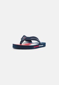 Infradito in gomma blu navy con una fascia testurizzata, caratterizzati da un motivo a righe rosse e bianche sulla suola e un logo sulla fascia.