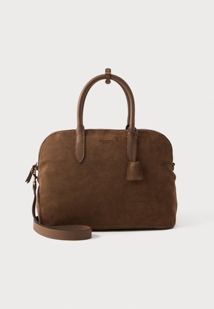 Geantă din suede maro cu mânere din piele netedă, fermoar superior, curea de umăr detașabilă și un mic accent suspendat. Formă rotundă, design minimalist.