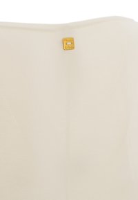 Tessuto a maglia crema con una superficie liscia, caratterizzato da un piccolo etichetta dorata sul retro. Il design è semplice e minimalista.