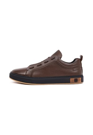 Lage bruine leren sneaker met zwarte zool, lichte rand van de buitenzool, vetergaatjes zonder veters, en trekkusje bij de hiel.