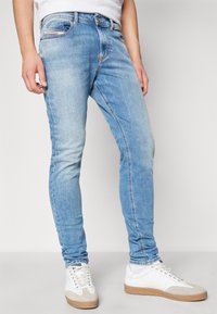 Ljusblå denimjeans med slim fit, kontrasterande sömmar och en urtvättad finish. Inkluderar en framficka och varumärkeslogotyp på midjebandet.