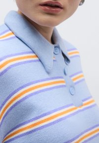 Ανοιχτογαλάζιο polo μπλουζάκι με κοντό μανίκι και γιακά, με ρίγες σε πορτοκαλί, μωβ και λευκό. Διαθέτει δύο ανοιχτογαλάζια κουμπιά.