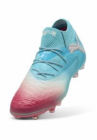 Jasnoniebieskie i różowe gradientowe korki piłkarskie z teksturowaną cholewką, systemem sznurowania i logo po boku. Posiadają gumową podeszwę z korkami.