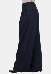 Pantaloni a gamba larga blu navy con vita alta, pieghe frontali e una tasca posteriore. Tessuto liscio con un taglio moderno.