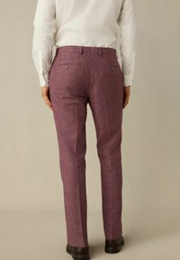 Lila strukturierte Hosen mit geradem Beinschnitt, ausgestattet mit zwei hinteren Taschen mit Knöpfen und getragen mit einem weißen Langarmhemd.