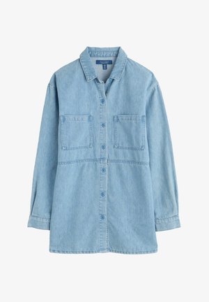 Camisa de mezclilla azul claro con frente abotonado, mangas largas, dos bolsillos en el pecho y cuello doblado. Presenta un dobladillo recto.
