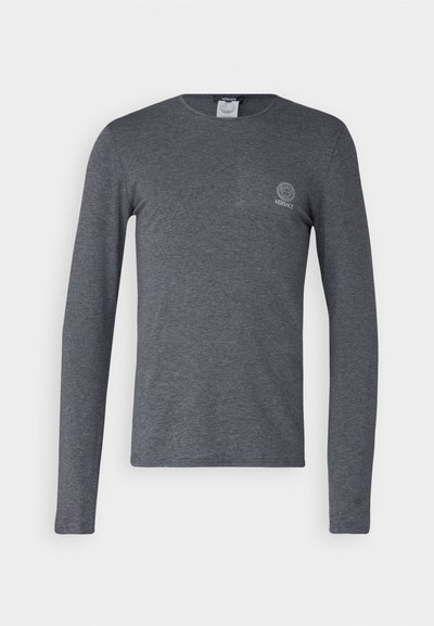 T-shirt à manches longues gris en tissu doux, avec un col rond et un petit logo sur la poitrine gauche. Texture lisse, coupe décontractée.