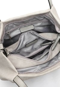 Sac en toile de couleur gris clair, doté de plusieurs compartiments zippés, d'une texture douce et d'un motif logo intérieur subtil.