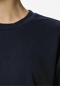 Mörkblå bomulls t-shirt med rund halsringning och en mjuk yta. Nära vy av tyget och krags detaljer.