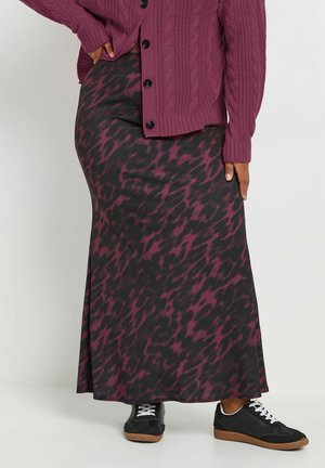 Gonna maxi nera con un motivo astratto multicolore in bordeaux, abbinata a un cardigan in maglia a trecce e sneakers nere, bianche e con suola in gomma.