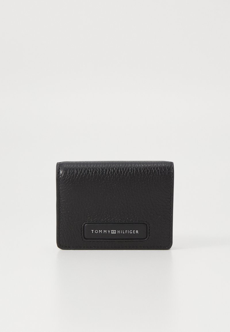 Black leather wallet with a textured finish, featuring a rectangular logo patch that reads "TOMMY HILFIGER" in white. Compact design.