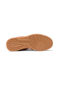 Podešev bot Reebok má strukturovaný gumový základ v béžové barvě s texturovaným gripem a logem značky, navrženým pro trakci a trvanlivost.