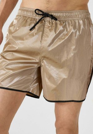 Lichtbruine, glanzende zwembroek gemaakt van een glad materiaal, met een elastische tailleband en een zwarte trekkoord en contrasterende zwarte afwerking.