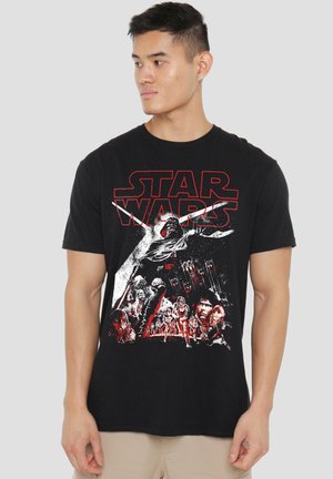 Young man wearing a black Star Wars t-shirt featuring red and white graphic of characters and logo, looking to his left.