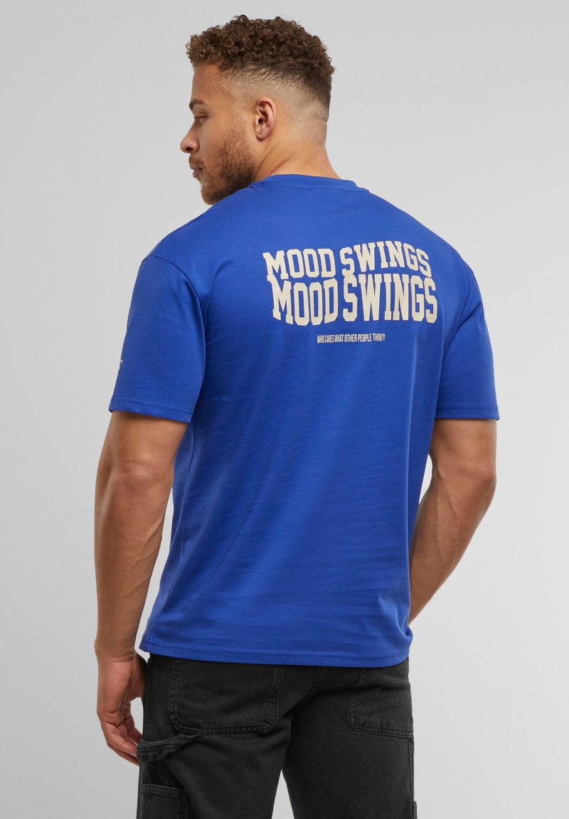 Blå bomulds T-shirt med "MOOD SWINGS" trykt tydeligt i hvid på ryggen, kortærmet og med rund halsudskæring.
