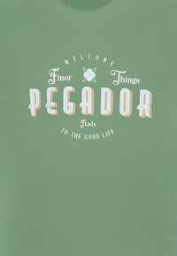 Green cotton sweater featuring a graphic with the text "WELCOME Finer Things PEGADOR Italy TO THE GOOD LIFE" in various colors.