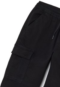 Zwarte cargobroek met elastische tailleband, trekkoord, zijzakken en een klepzak op de dij, weergegeven op een witte achtergrond.