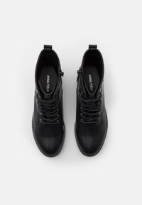 Botas de tobillo de cuero negro con cordones, punteras redondeadas y cremalleras laterales decorativas. Textura suave y diseño minimalista, con una plantilla de marca.