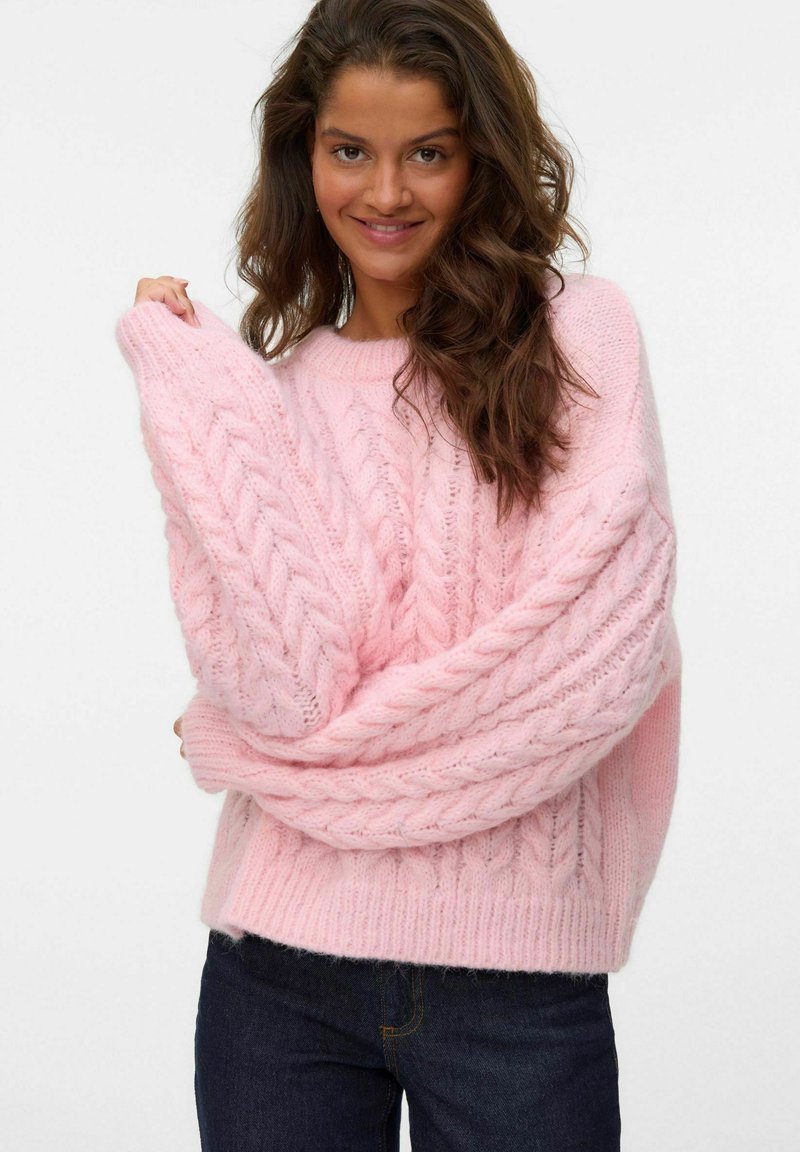 Pull en tricot rose avec un design en torsade, coupe oversize et poignets côtelés, avec une texture douce et une apparence chaleureuse.