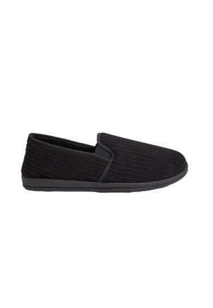 Zapatilla negra de pana tipo slip-on con un diseño de bajo perfil, superficie texturizada y suela de goma negra. Sin herrajes ni acentos visibles.