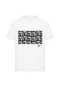 Hvid bomuld t-shirt med et gitter af sort-hvide illustrationer af en alienfigur, med teksten "E.T." nederst til højre.