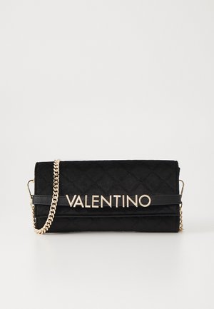 Sac en daim matelassé noir avec quincaillerie dorée, une bandoulière en chaîne et un logo « VALENTINO » en évidence sur le devant.