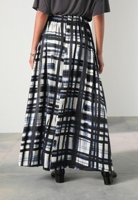 Gonna maxi in plaid nera, bianca e blu, realizzata in tessuto morbido con vita elastica e una silhouette fluida.