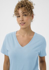 Hellblaues V-Ausschnitt-T-Shirt aus weichem Stoff, mit kurzen Ärmeln und lockerer Passform. Glatte Oberfläche ohne Muster oder Akzente.