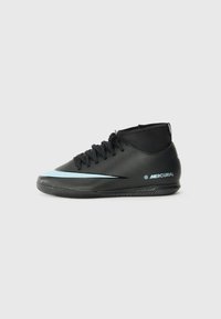 Chaussures de football noires avec un design montante, présentant une rayure d'accent bleu clair, une surface texturée et une semelle extérieure en caoutchouc à motifs.