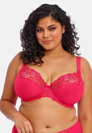 Pink bra featuring sheer embroidered lace at the top, matching underwire, and adjustable straps. Smooth fabric with floral pattern accents.