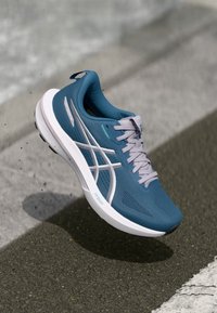 Teal løpesko med mesh-overdel, hvite elementer og snøringer. Har en tykk såle med "FF Blast"-merke, teksturert design for grep.