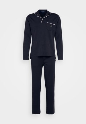 Conjunto de pijama azul-marinho com uma blusa de manga longa, gola, bolso e detalhes em branco, combinado com calças retas a condizer. Material em algodão.