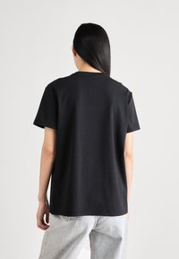 Svart bomull T-skjorte med rund hals og korte ermer, med en avslappet passform og jevn tekstur, kombinert med lyse jeans.