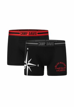 Zwei Paar Herrenboxershorts aus schwarzem Stoff. Eine hat einen roten Bund mit dem Text "CAMP DAVID"; die andere zeigt ein Kompassdesign und ein Logo in Grau und Rot.