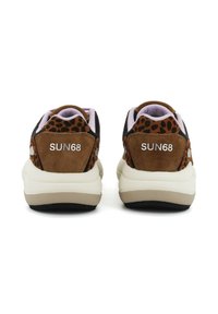 Sneaker in suede marrone con accenti in tessuto nero, dettagli in stampa leopardata e logo bianco sul tallone. Suola spessa bianca con suola nera.