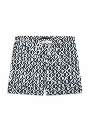 Marineblå og hvide badeshorts med geometrisk starburst-mønster og hvid snor i taljen, lagt fladt på hvid baggrund.
