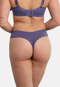 Purple brief with scalloped trim, made from soft, stretchy fabric. Features a smooth waistband and minimal rear coverage design.